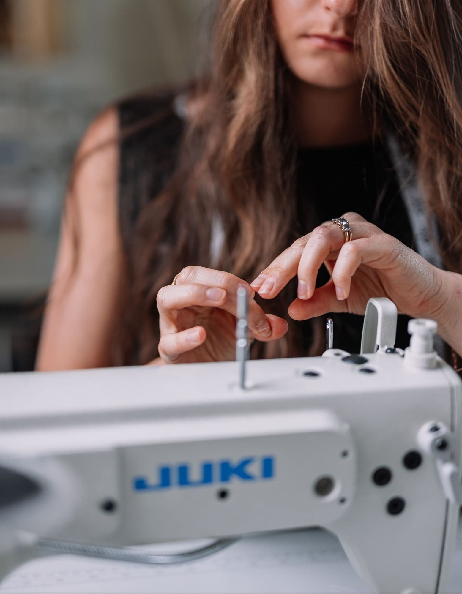 Samantha Covey threading a needle beside a Juki sewing machine.