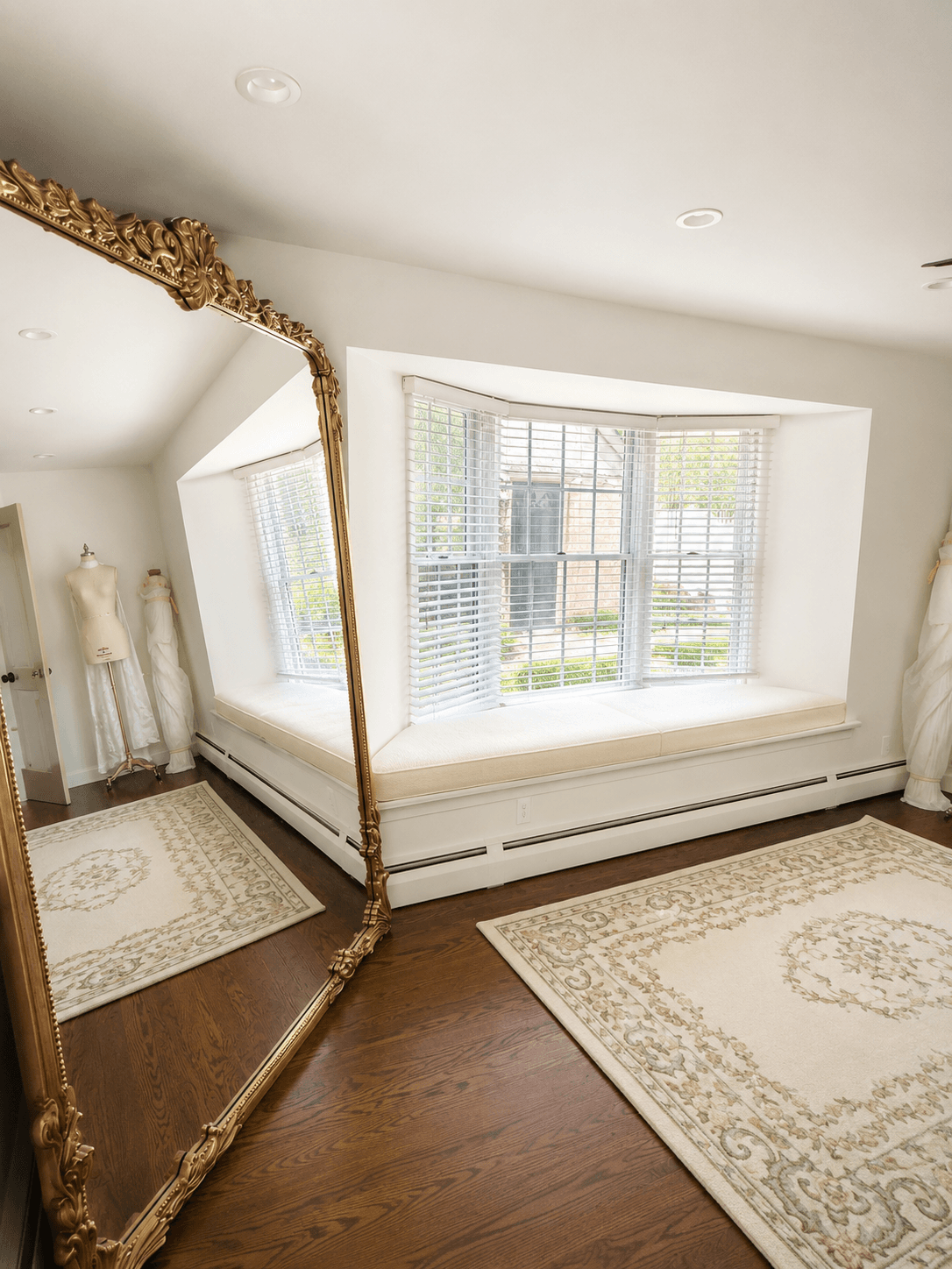Samantha Covey home studio with a full-length gold mirror and window seating.