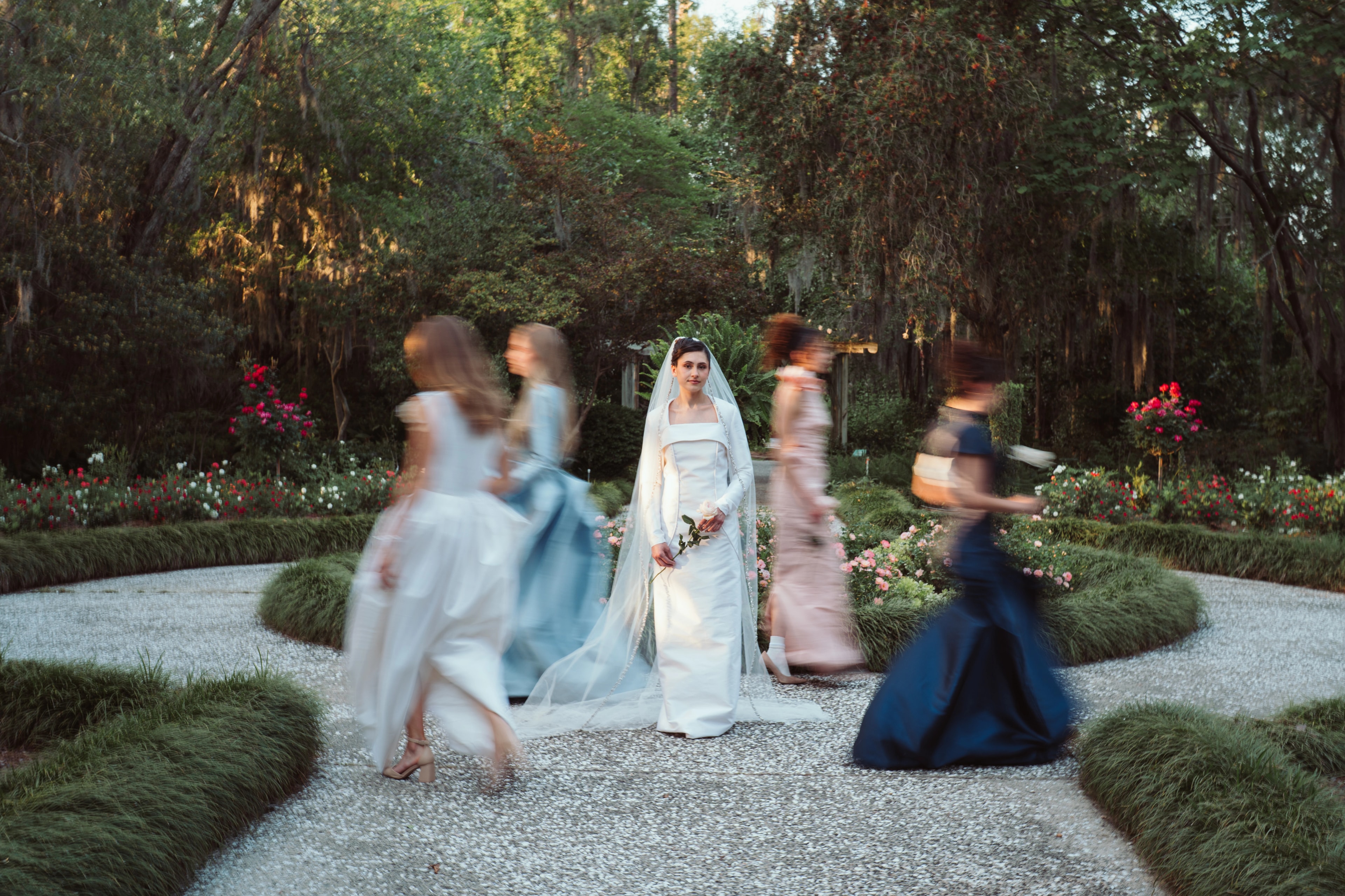 Niah fitted wedding dress in an editorial garden scene with figures in motion