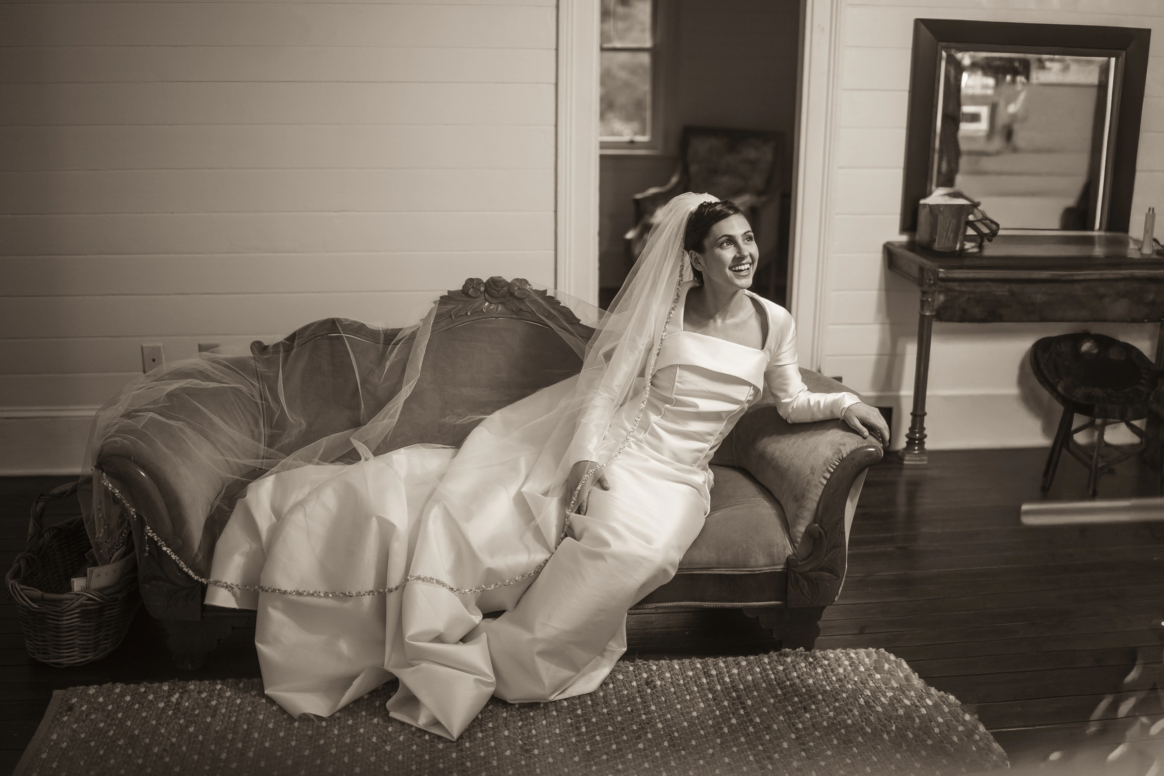Black-and-white bridal portrait showing Niah gown and cathedral veil draped across a settee