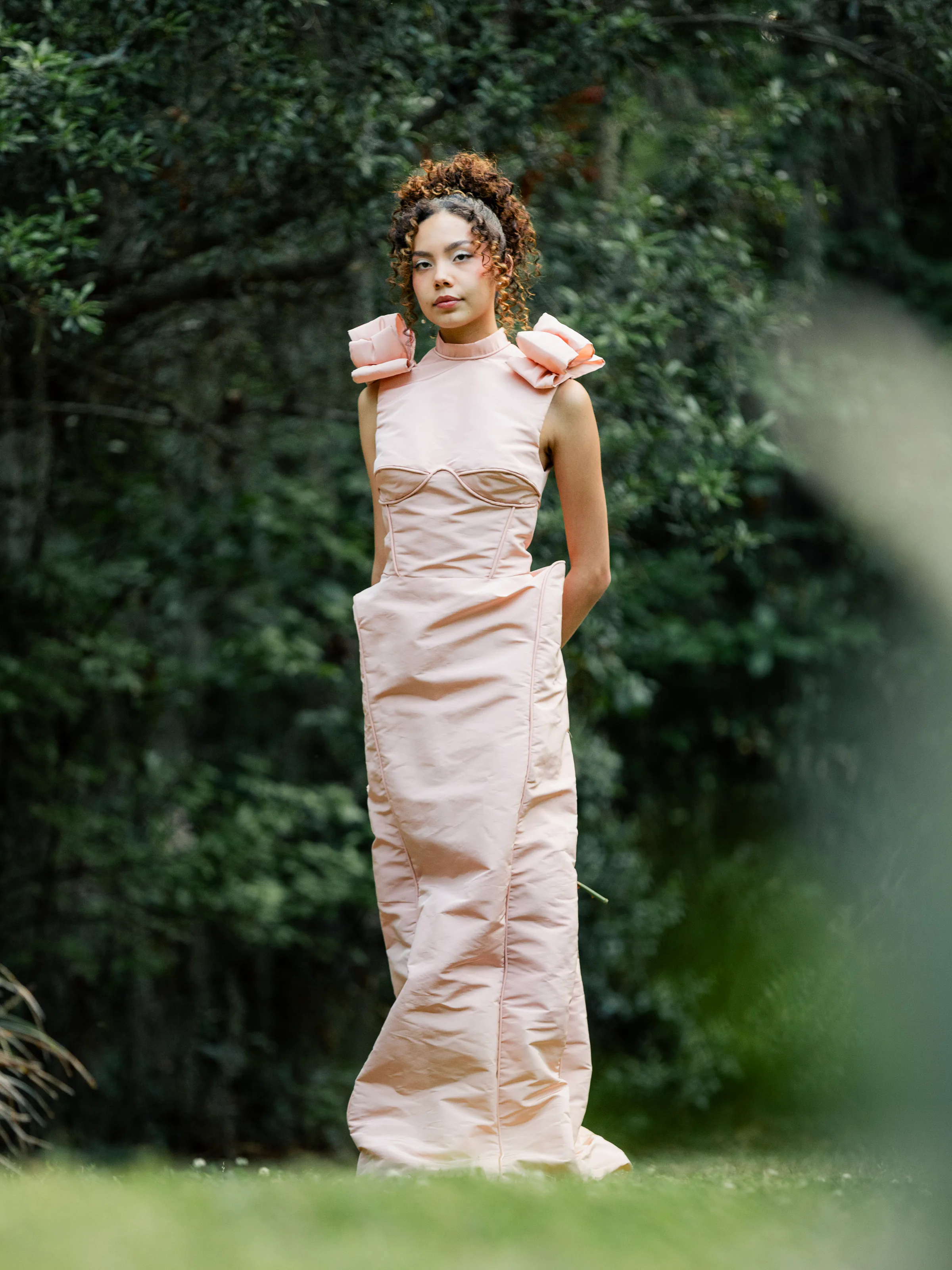 Model wearing Rosalie, a blush satin column gown with sculpted rose shoulders and tonal corset seams