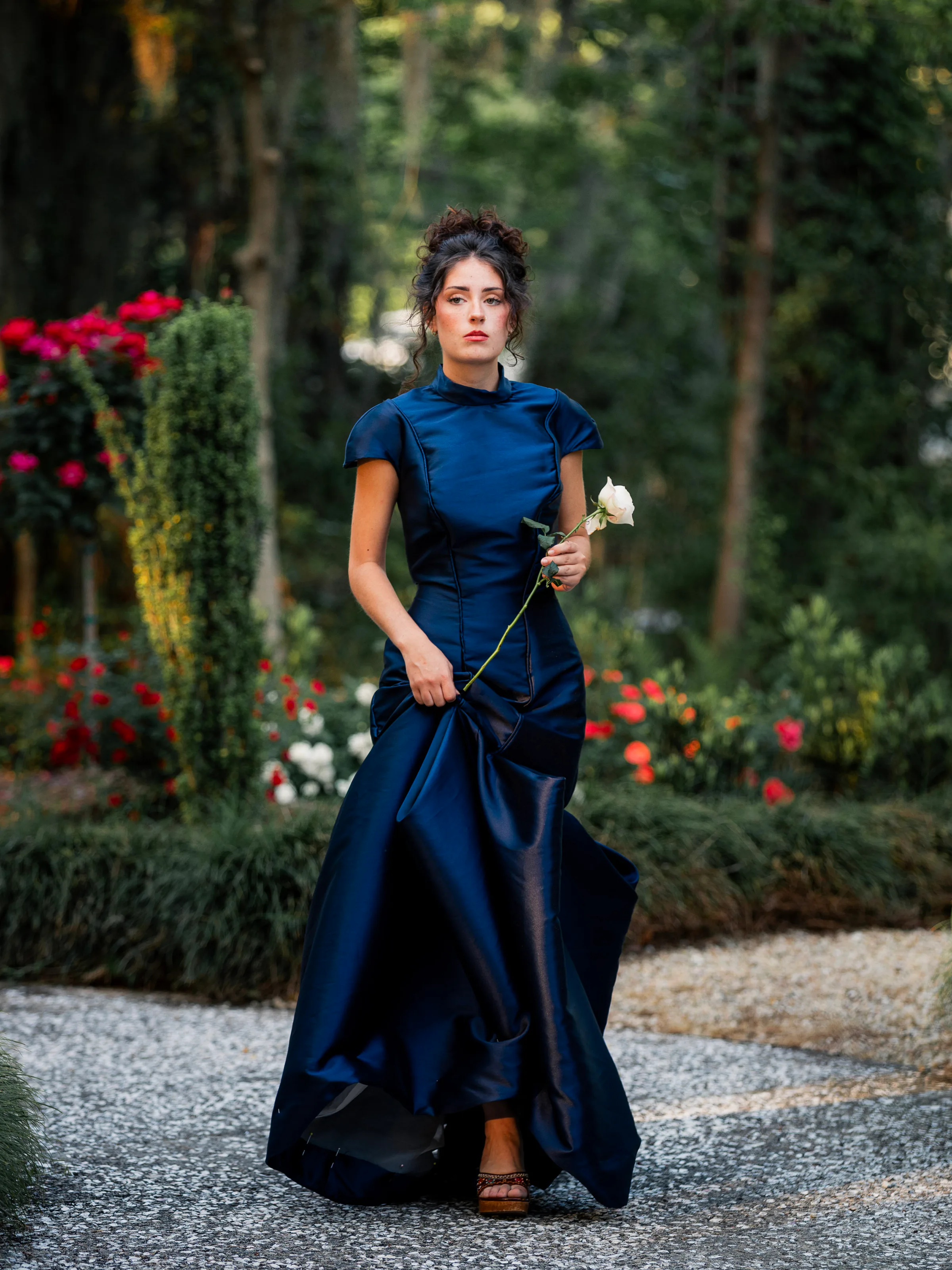 Model wearing Vesper, a midnight navy satin evening gown with a draped high neck and sculptural skirt