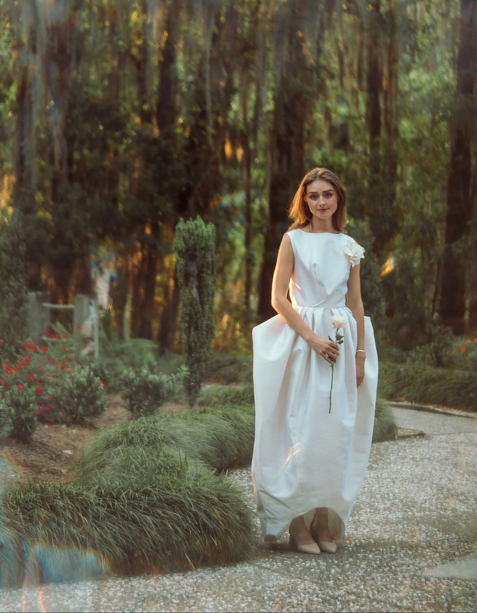 An ivory sleeveless gown on a garden path at sunset.