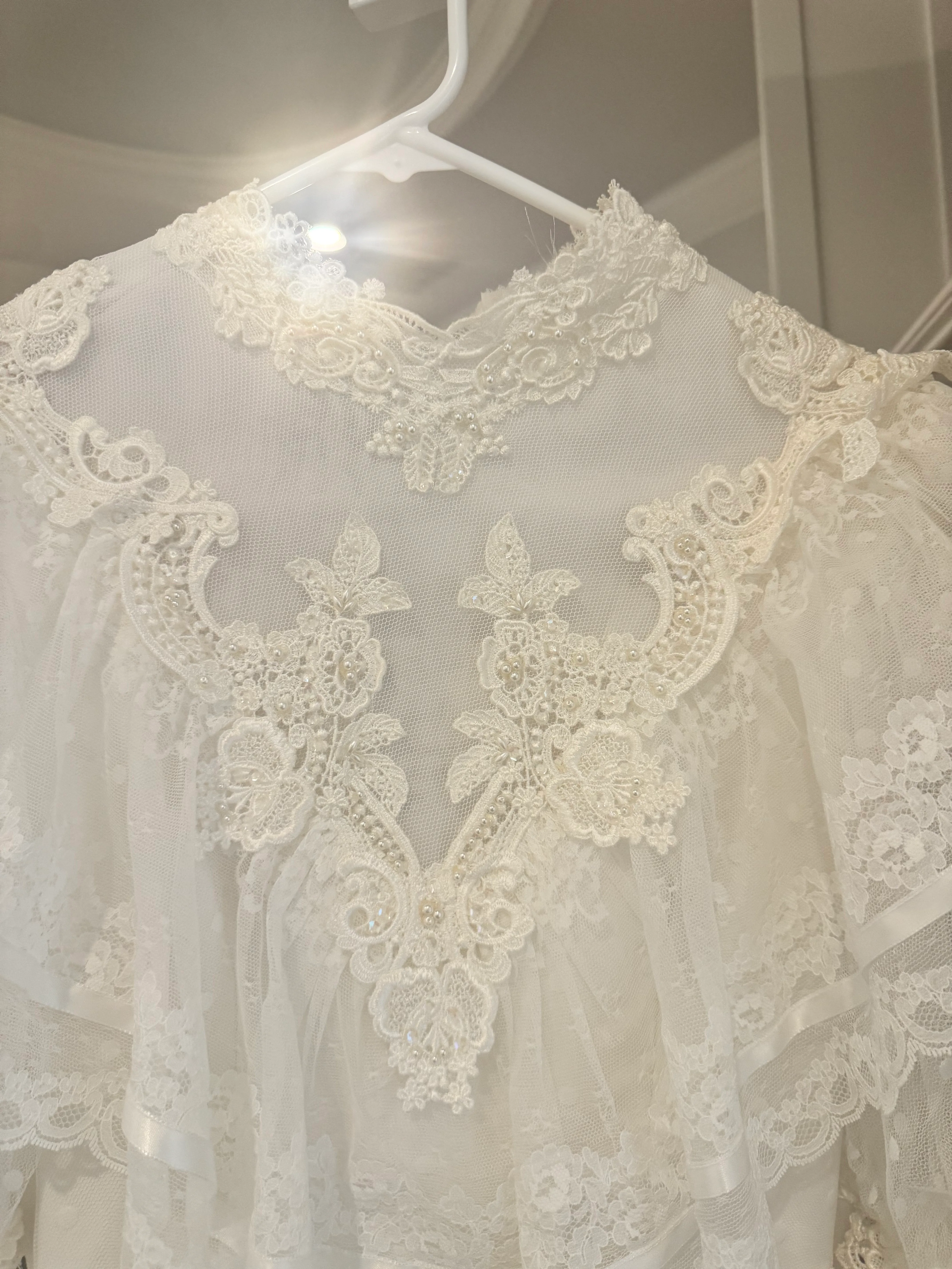A process detail of the lace bodice and sheer neckline on a hanger.