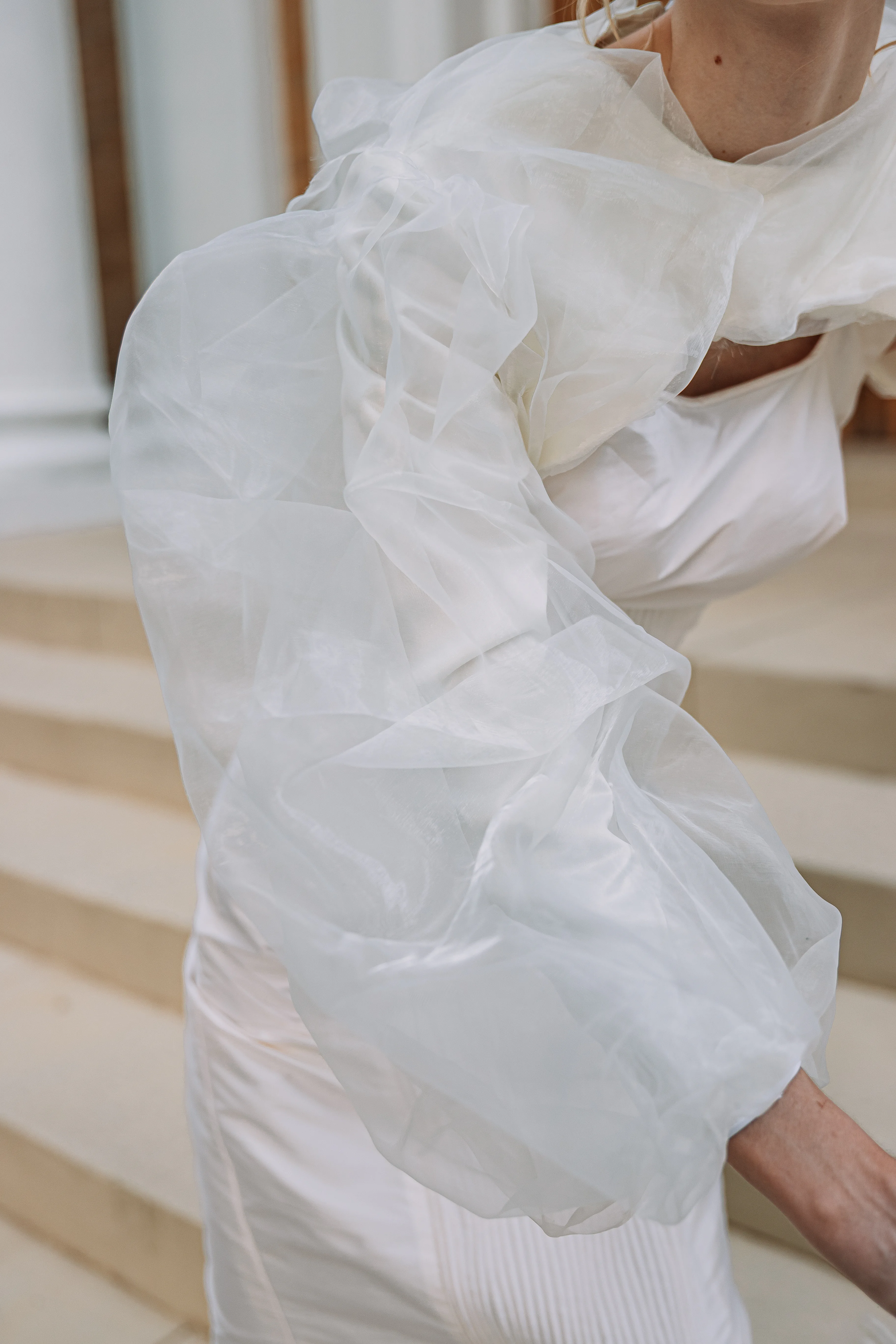A close detail of the sheer white organza sleeve volume and neckline layers on The White Project dress.