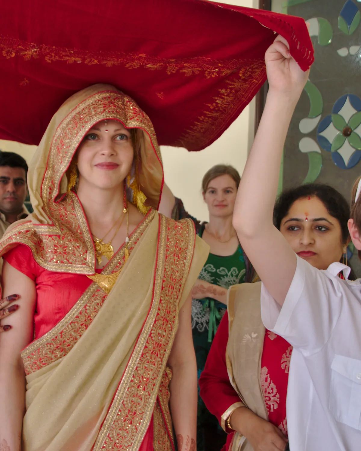 A Hindu bride in a sari being led toward a mandapa ceremony.