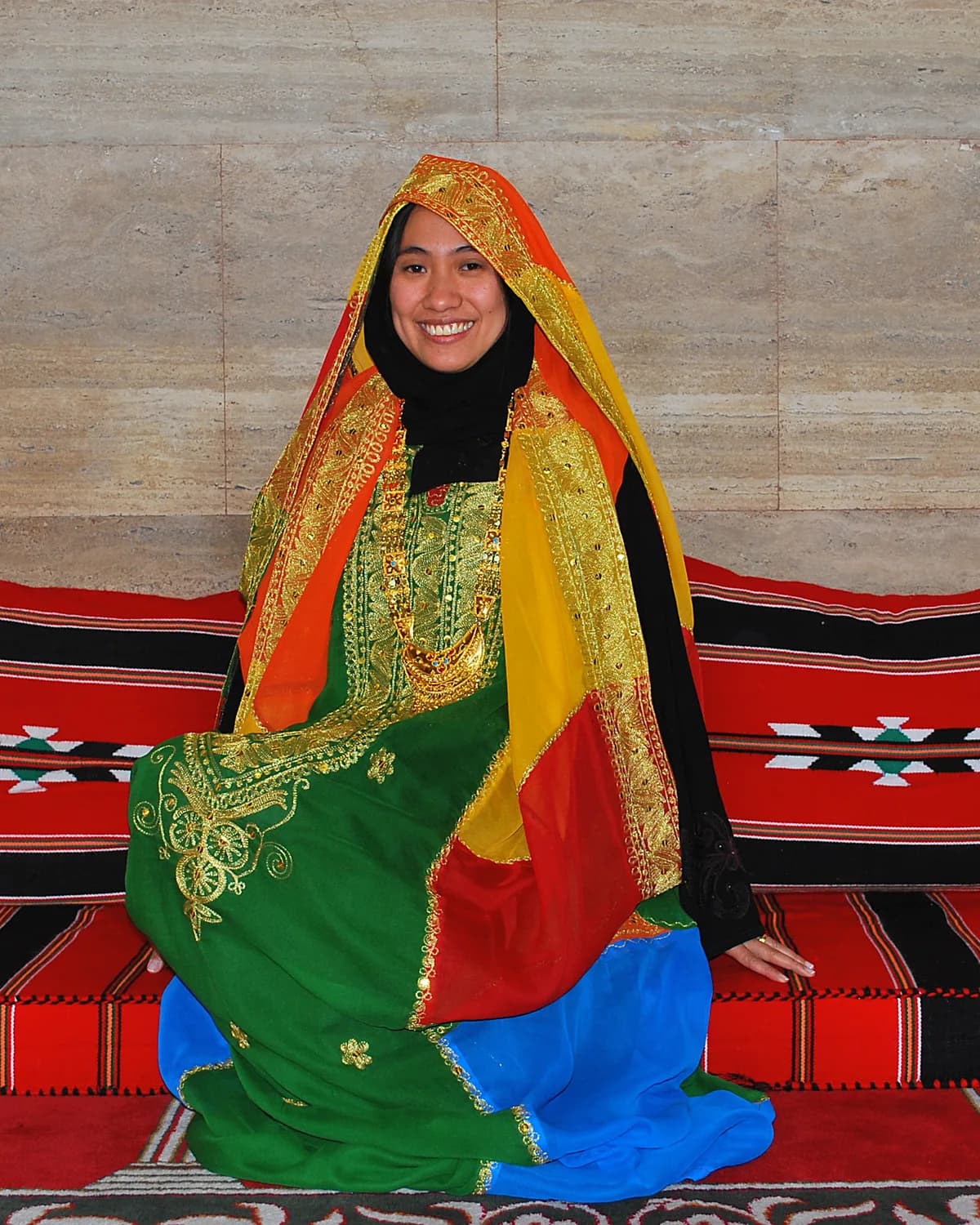A woman wearing a colorful Bahraini wedding costume with a head covering.
