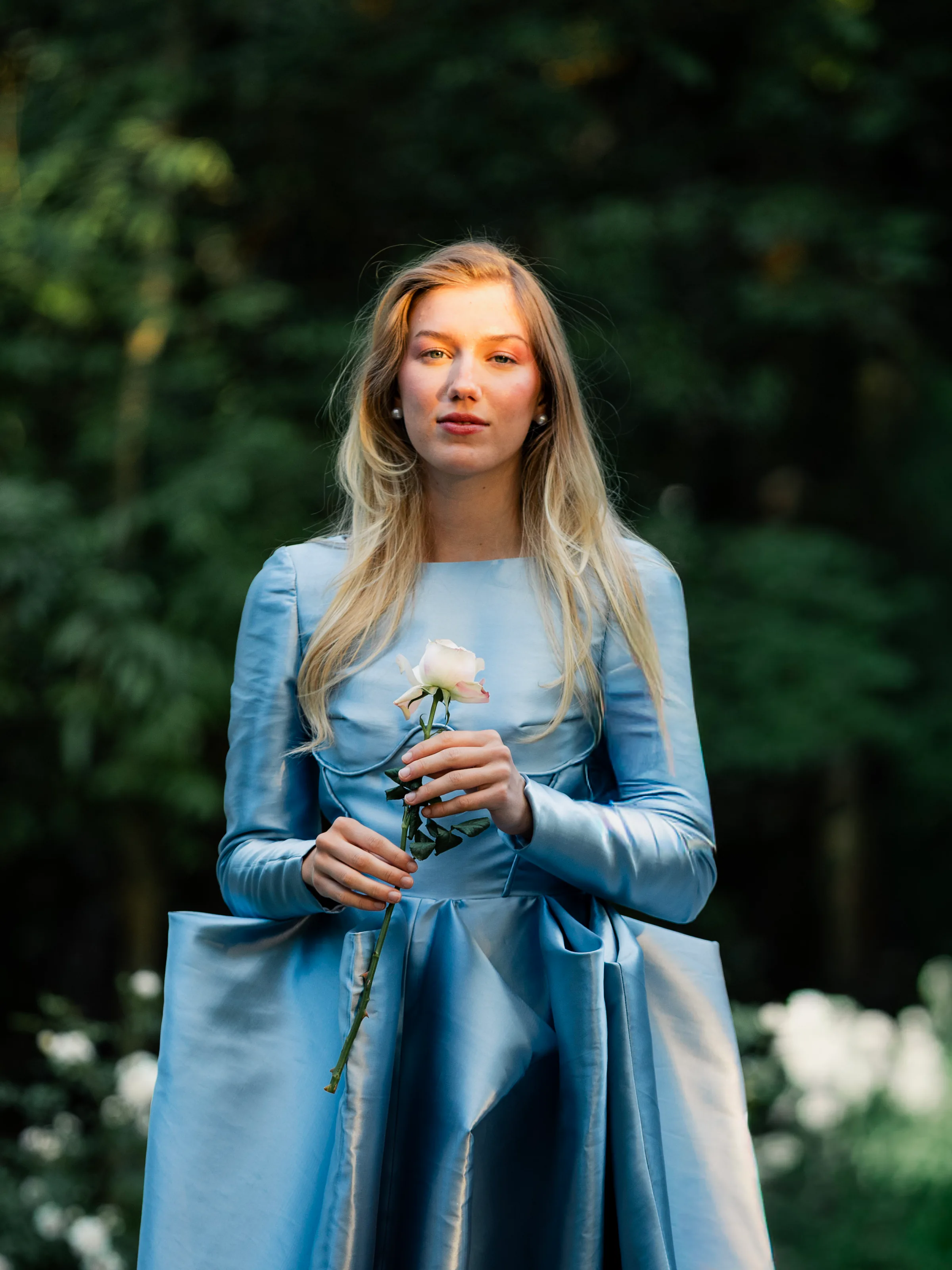 Close garden portrait showing Isolde's curved satin bodice seams and full-length sleeves