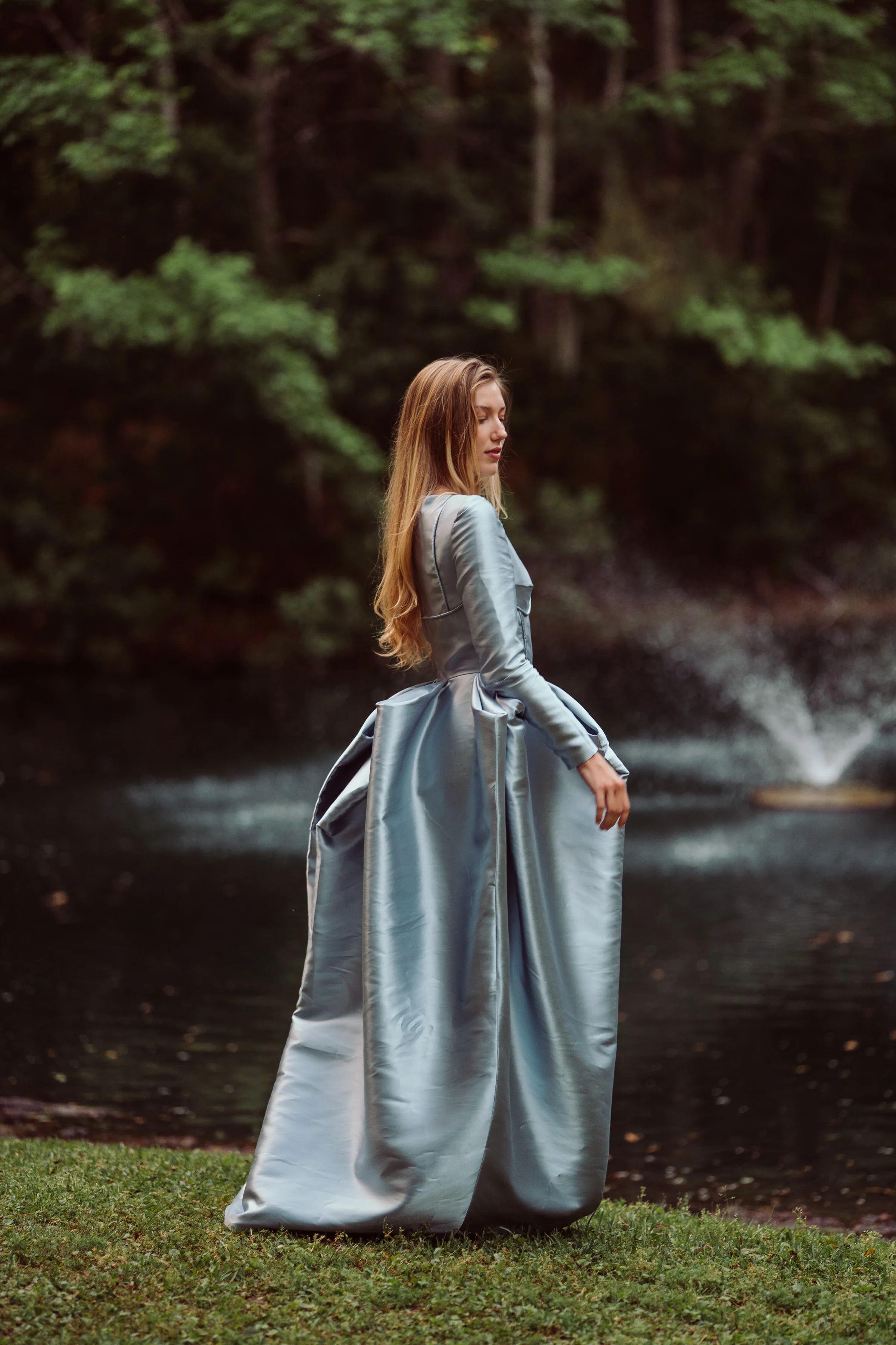 Side portrait of Isolde showing the fitted long-sleeve bodice and sculpted silver-blue skirt