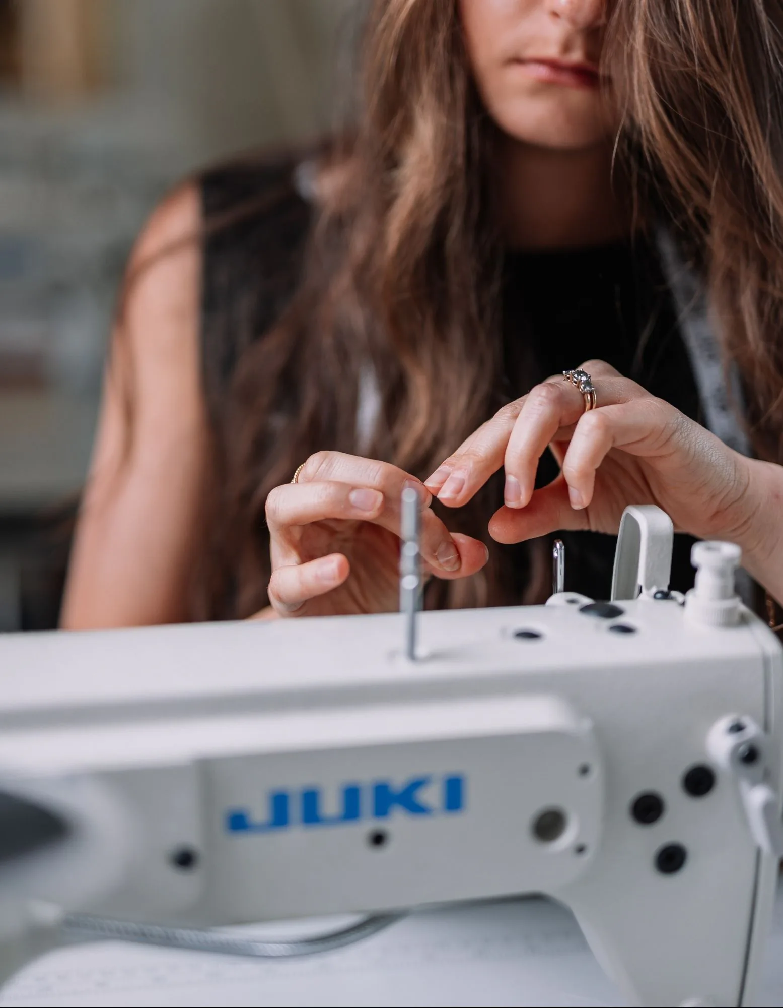 Samantha Covey threading a needle beside a Juki sewing machine.