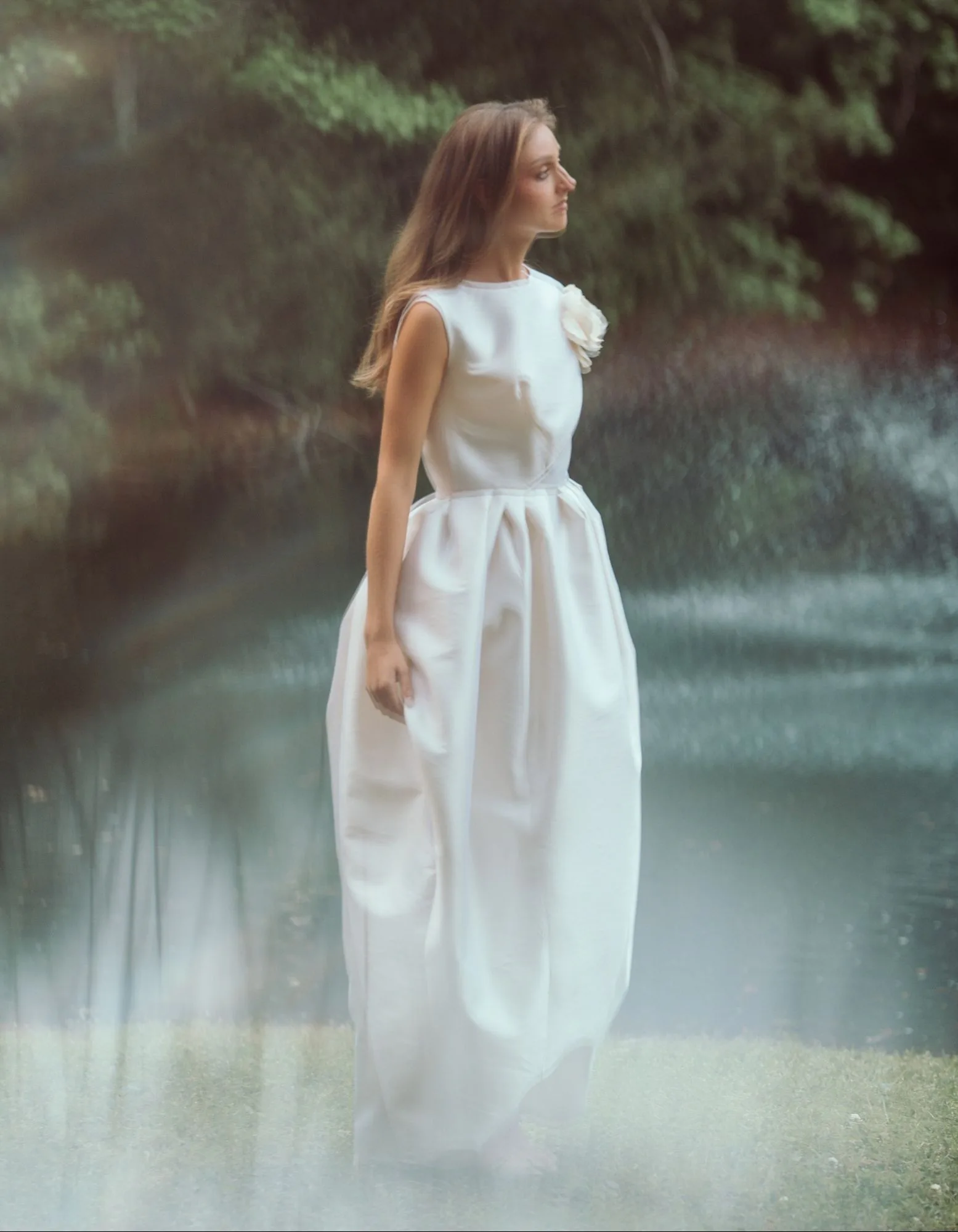 An ivory sculptural gown reflected beside the water.
