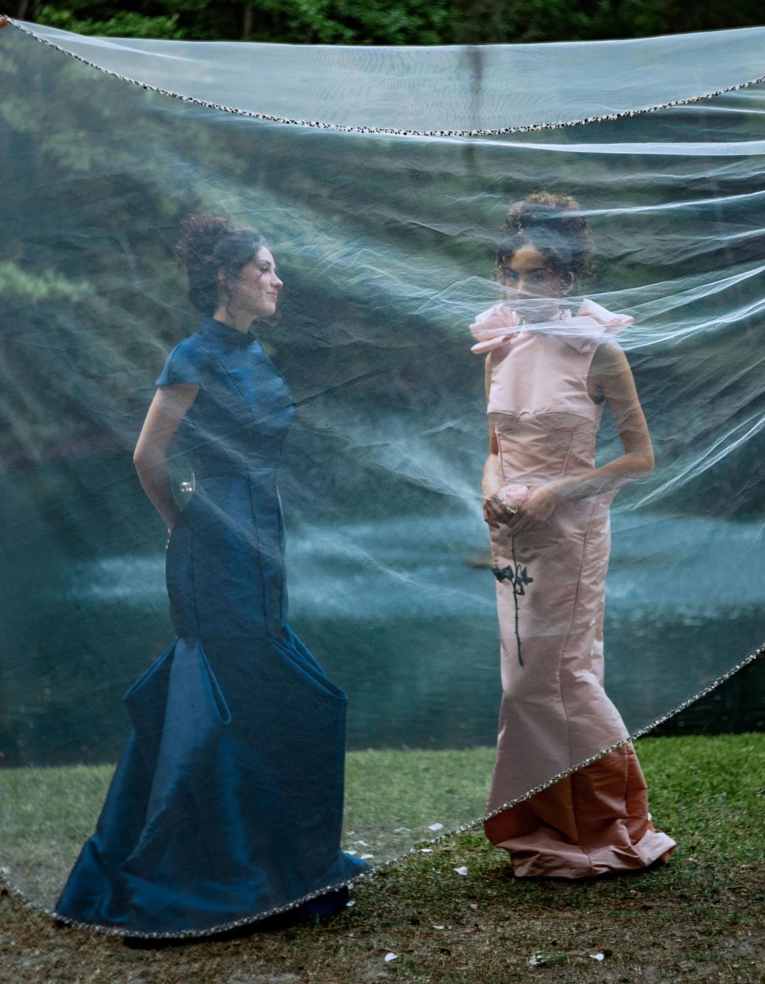 Blush and navy gowns seen through a veil draped across the scene.