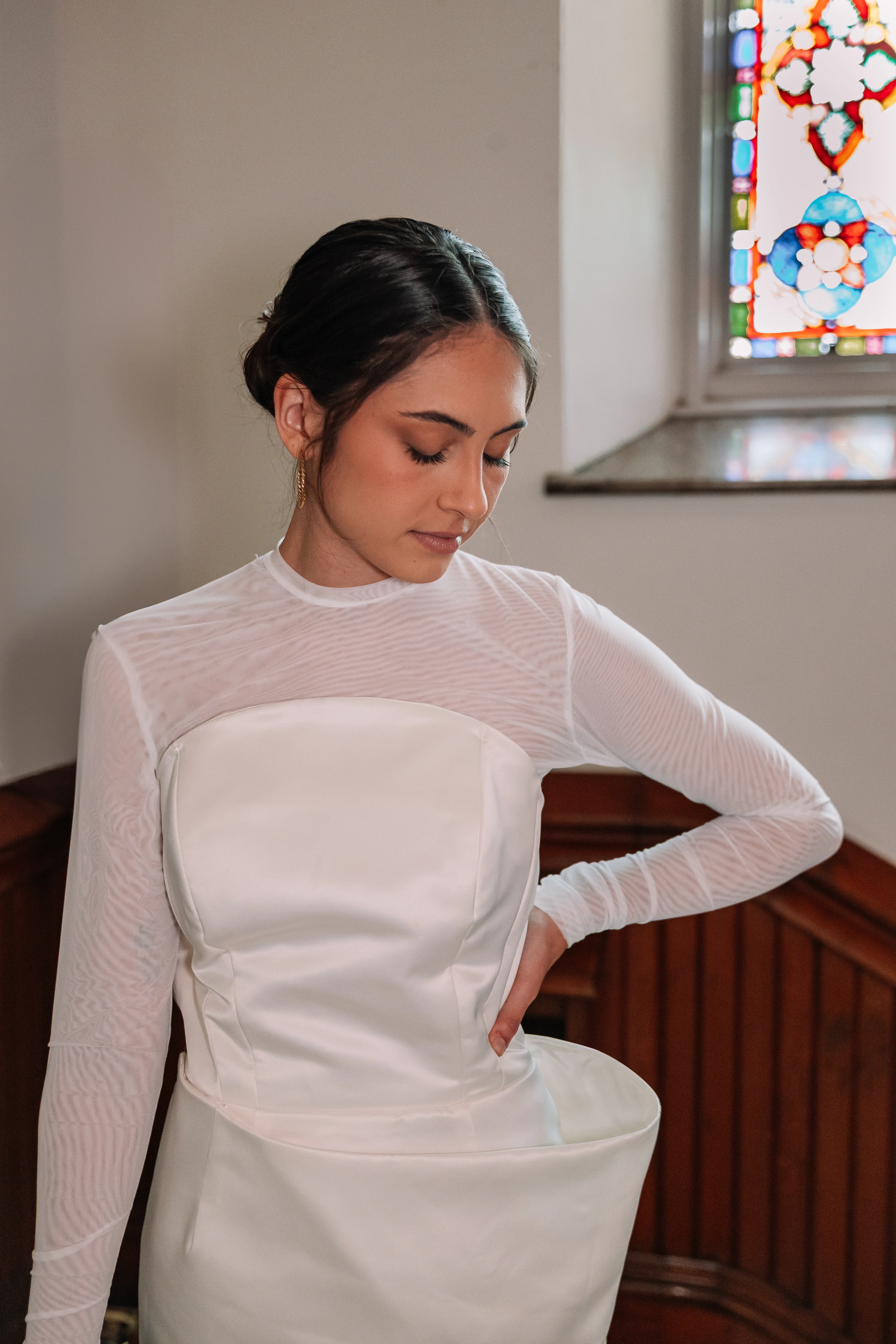 A portrait of the asymmetrical wedding dress with sheer long sleeves and a sculpted satin bodice.