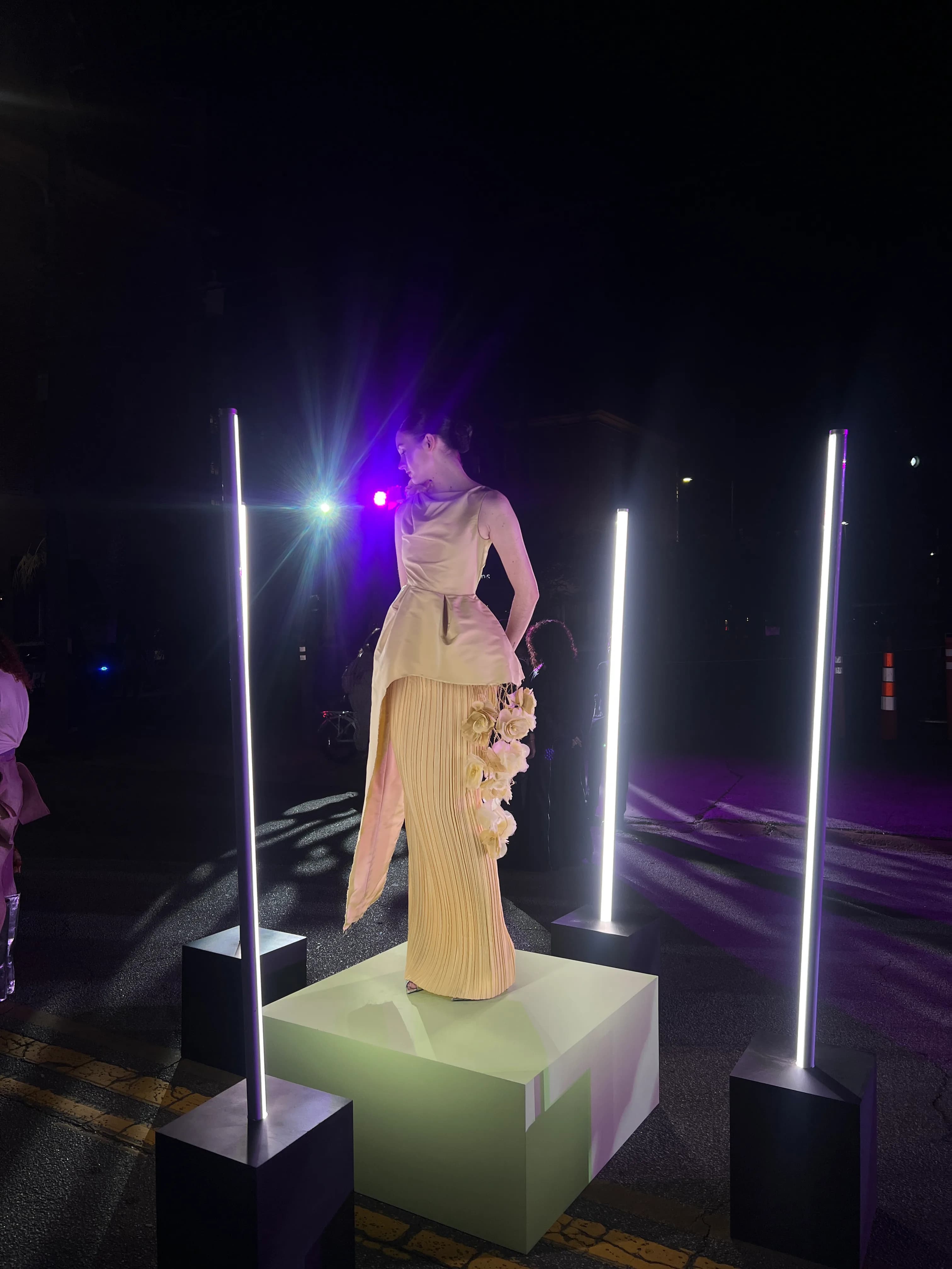 The yellow Lanvin-inspired look displayed outdoors at night between glowing light columns.