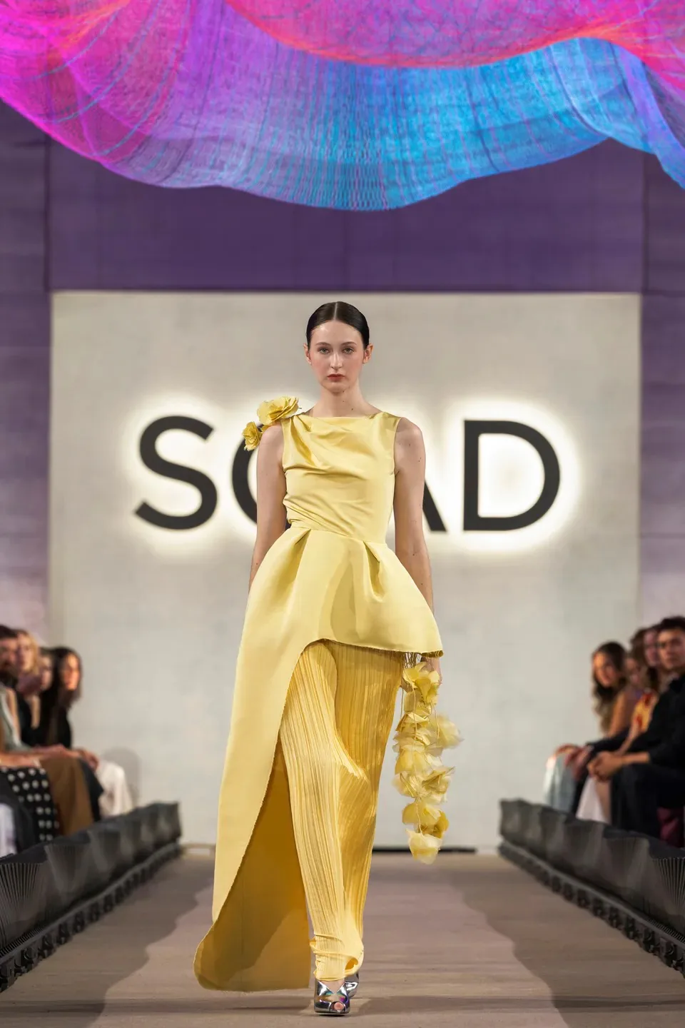 A model walking the SCAD Fashion Show runway in Samantha Covey's yellow Lanvin-inspired eveningwear look.