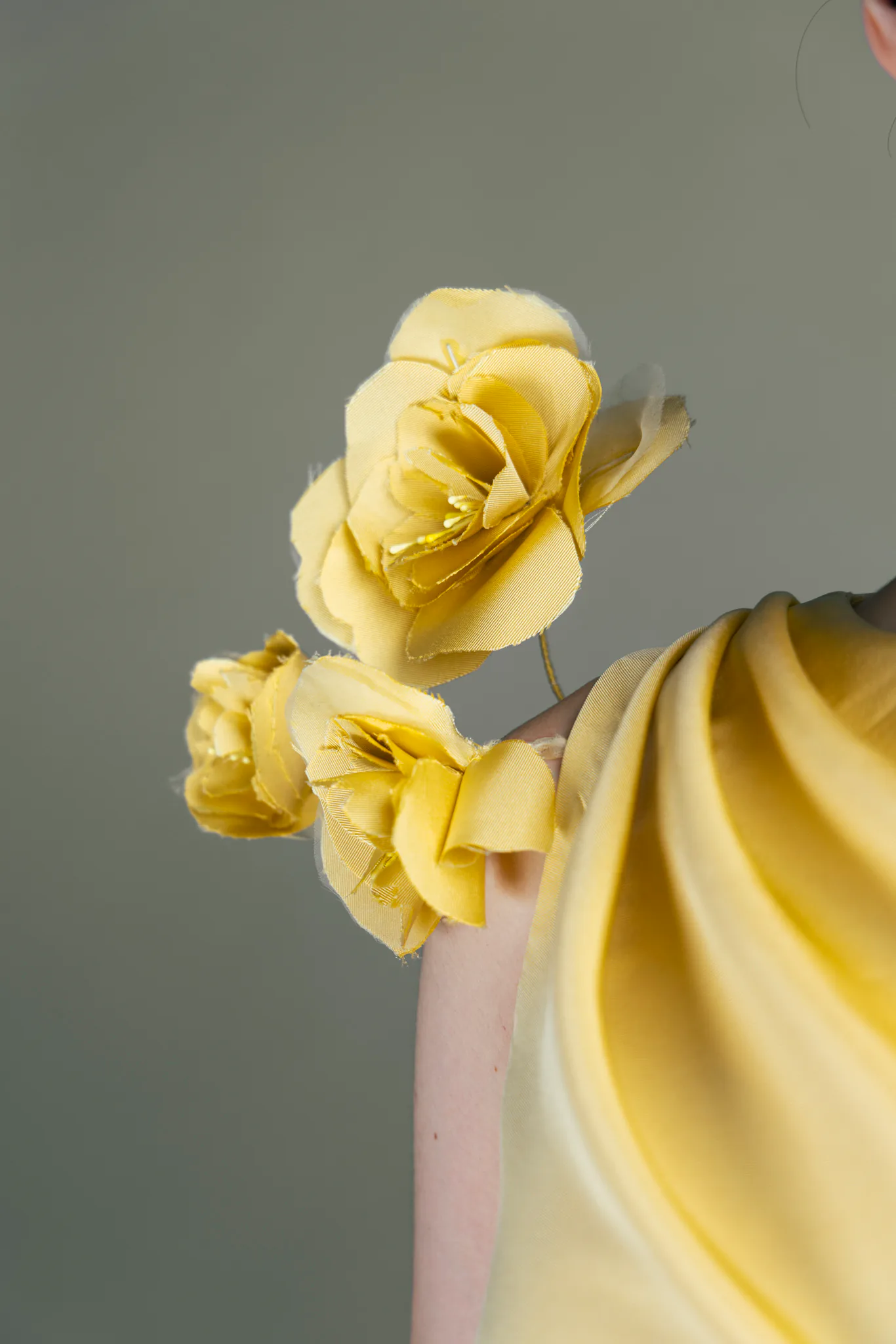 A close detail of yellow handmade flowers rising from the shoulder of the dress.